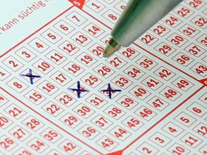 Pen is used to cross out numbers on a lottery card, thus selecting Lotto Numbers